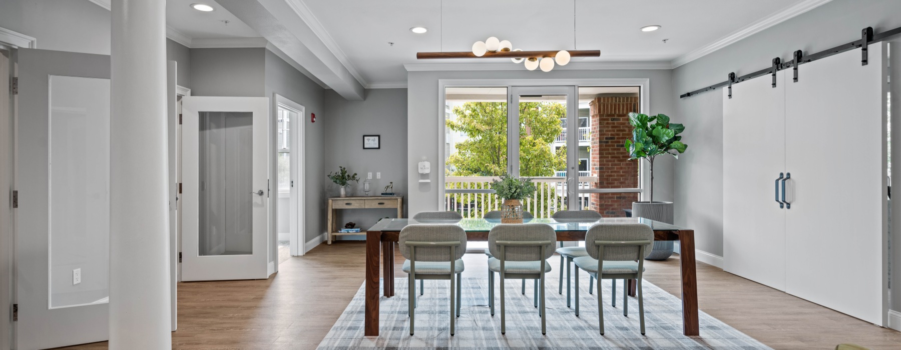 Clubhouse lounge with a long table, seating, and view of private co-working rooms