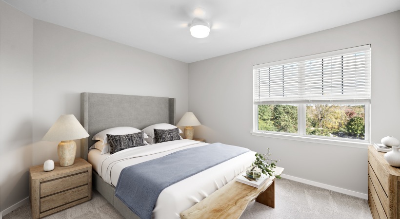 1 bedroom apartment for rent at The Avens at Dedham Station featuring a queen size bed, two end tables, bench seating and large windows overlooking lush greenery