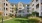 The courtyard at our apartments in Dedham, featuring green lawn, outdoor dining table with shaded umbrellas, and a view of the apartment community